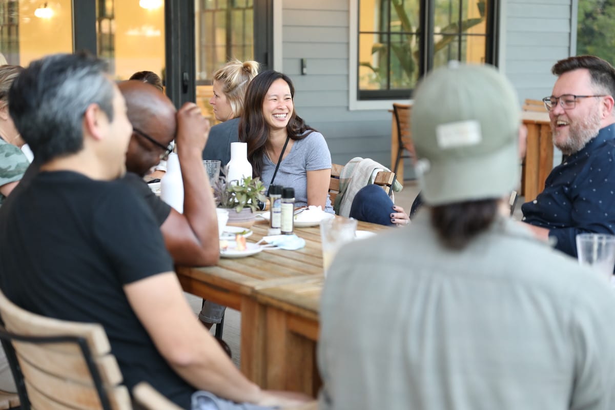 group of people smiling while sitting at a dining table