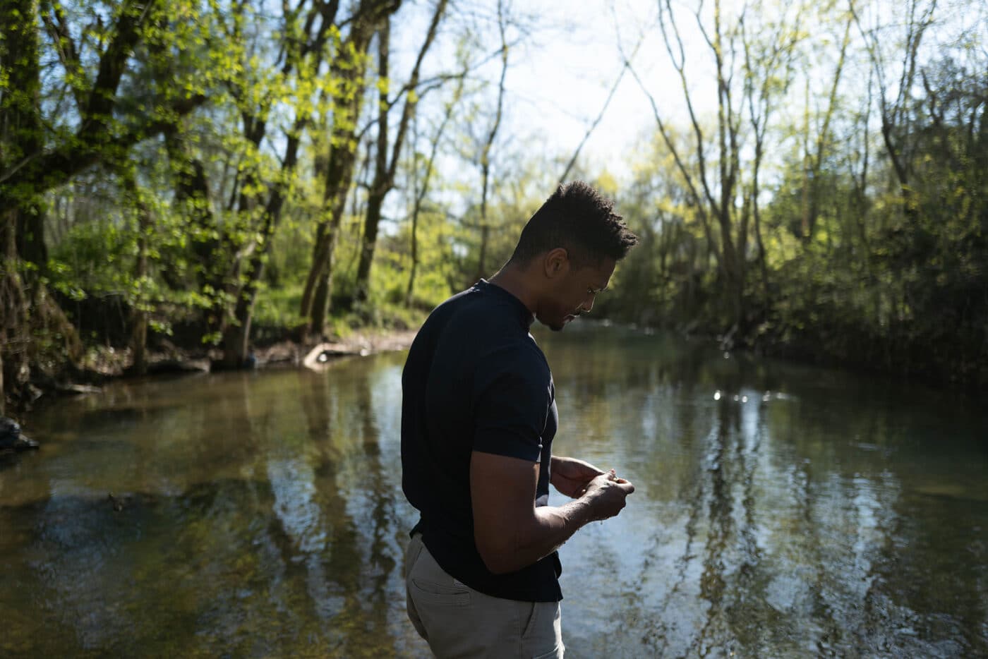 A man standing next to a creek in a forest