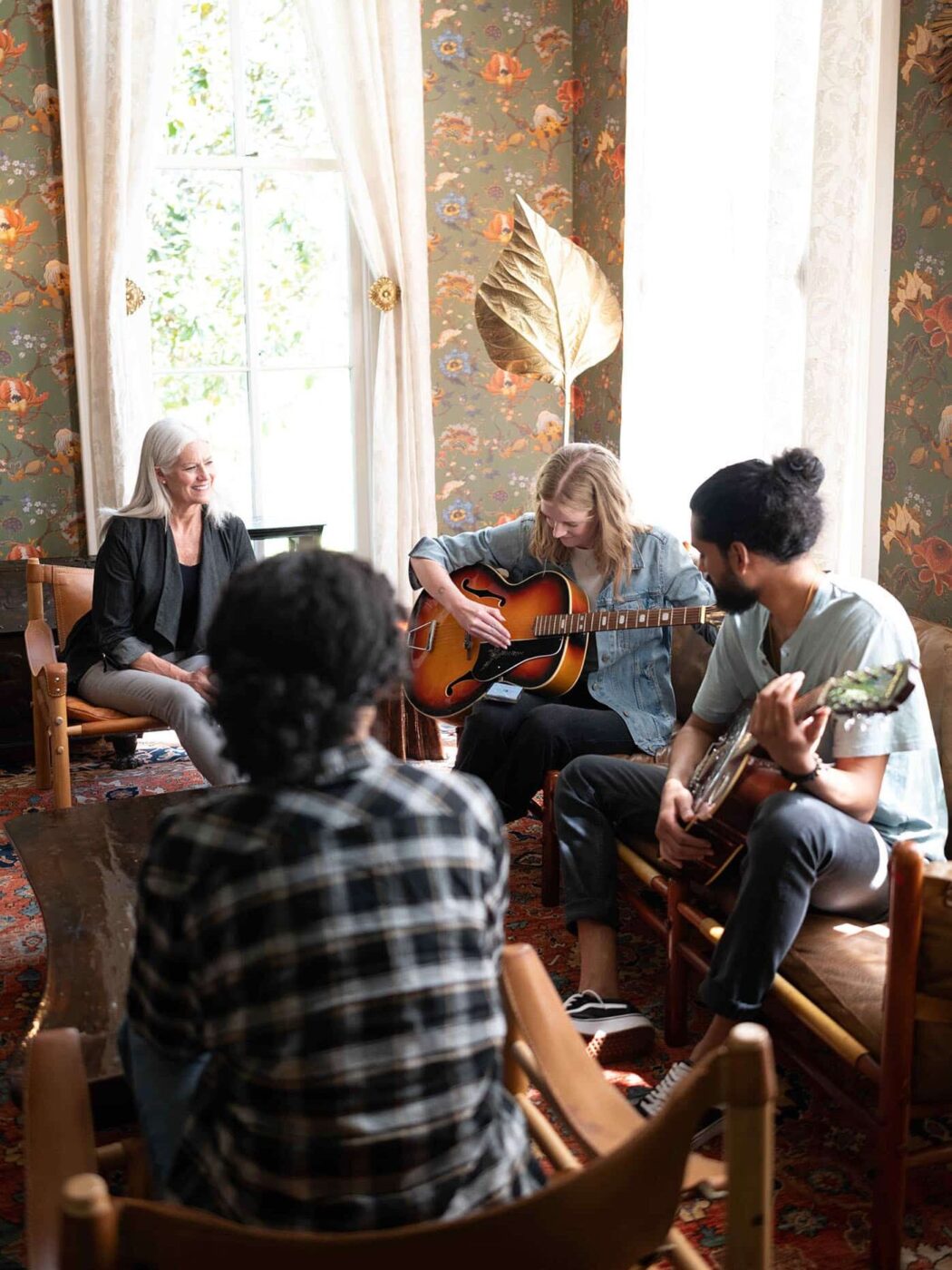 group of people sitting on sofa while a woman plays guitar