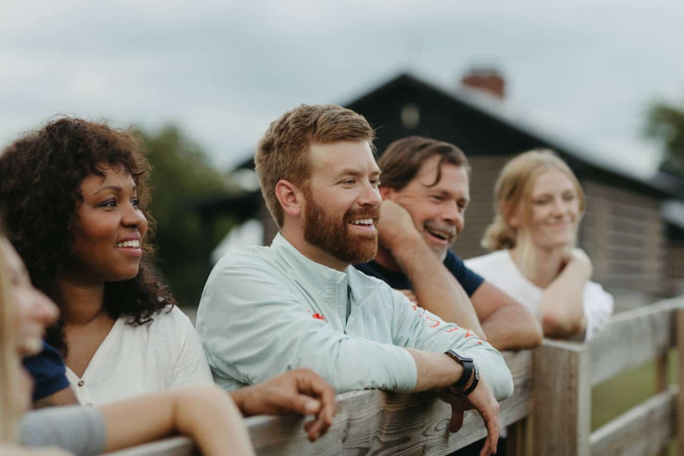 A group of people stand along a fence