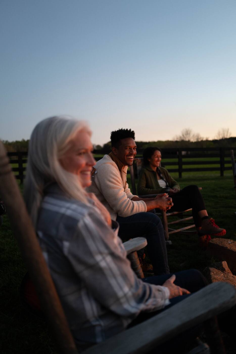 group of people in rocking chairs around bonfire