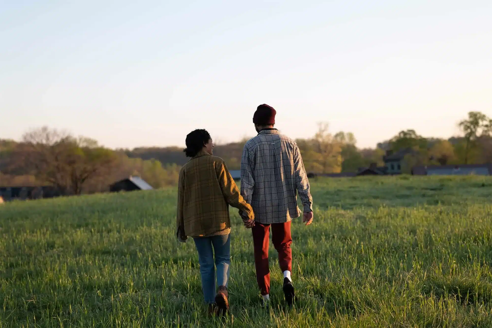 Two people holding hands taking a walk in a field